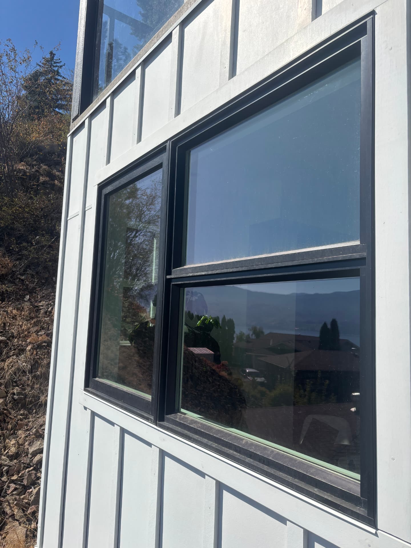 Dirty window with dusty frame and sill on white siding before cleaning