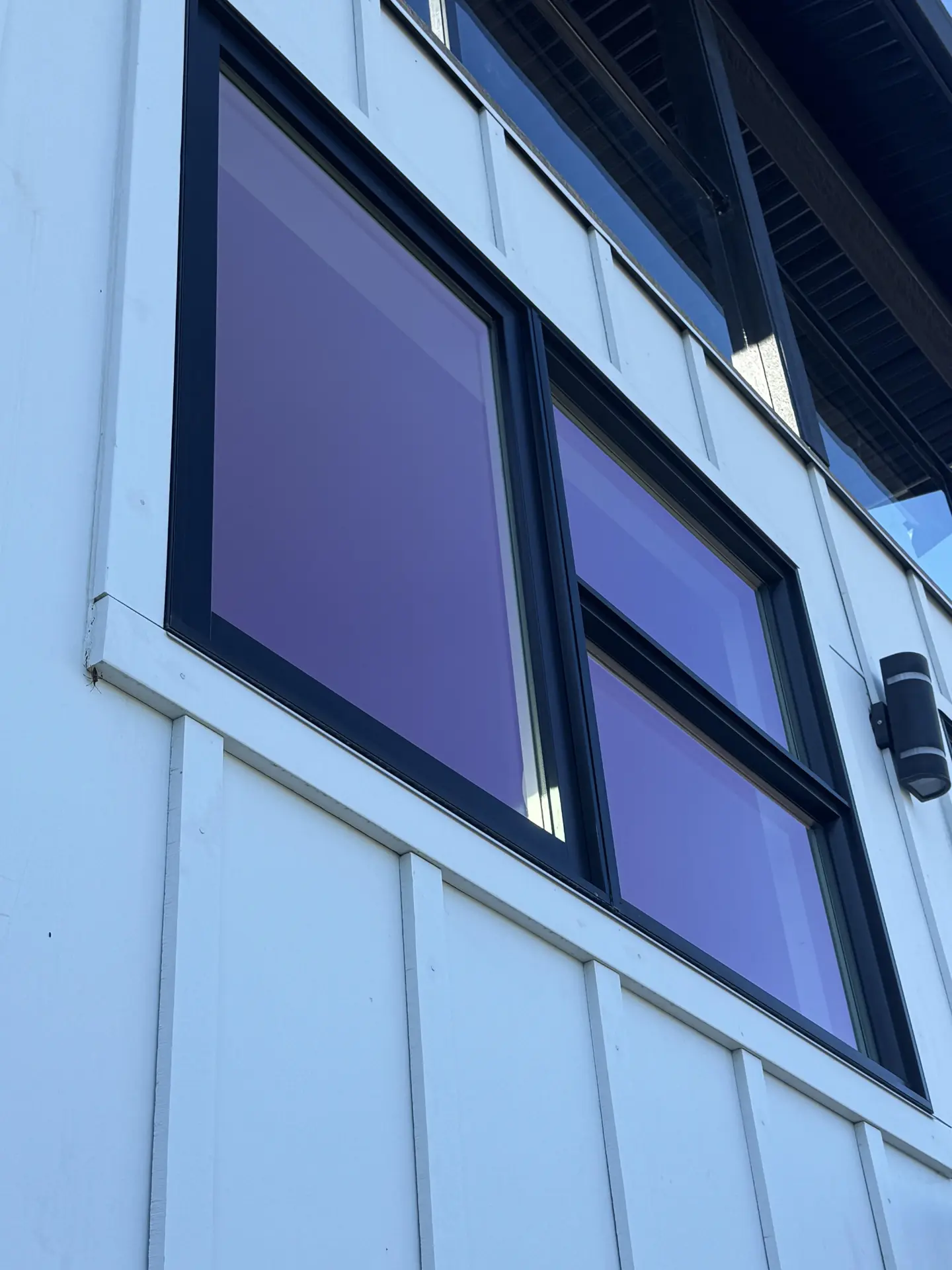 Clean window with black trim and white siding after exterior cleaning